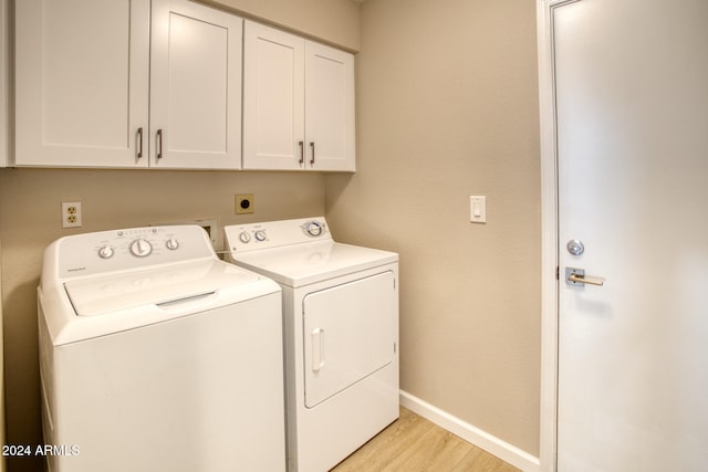 washroom with cabinets, washer and dryer, and light hardwood / wood-style flooring