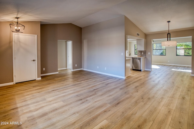 unfurnished living room featuring light hardwood / wood-style floors, sink, lofted ceiling, and a notable chandelier