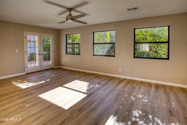 empty room with ceiling fan, french doors, and light hardwood / wood-style floors