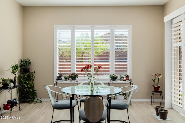 dining area featuring light wood-style flooring, baseboards, and a healthy amount of sunlight