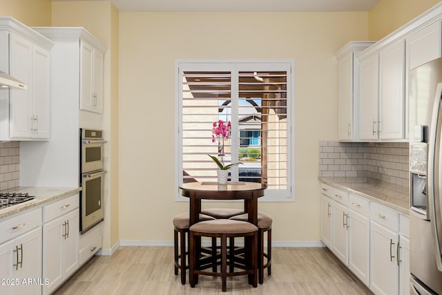 kitchen featuring backsplash, appliances with stainless steel finishes, white cabinetry, and baseboards