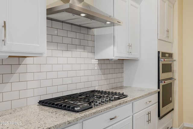 kitchen with stainless steel appliances, tasteful backsplash, range hood, and white cabinetry
