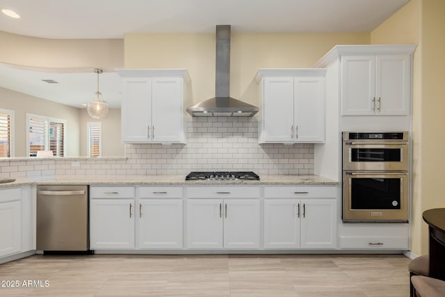 kitchen with white cabinetry, wall chimney range hood, backsplash, and appliances with stainless steel finishes