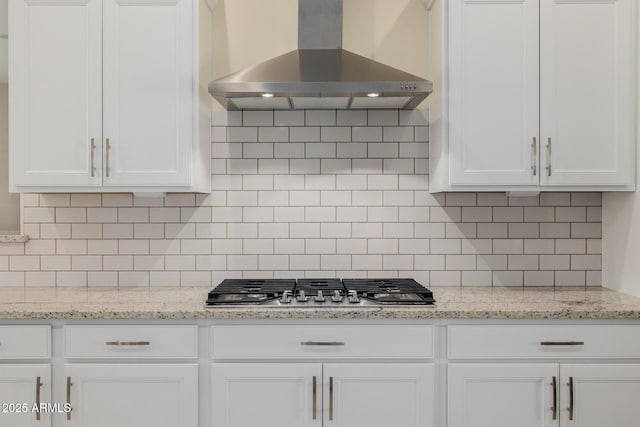 kitchen featuring stainless steel gas cooktop, wall chimney exhaust hood, backsplash, and white cabinetry