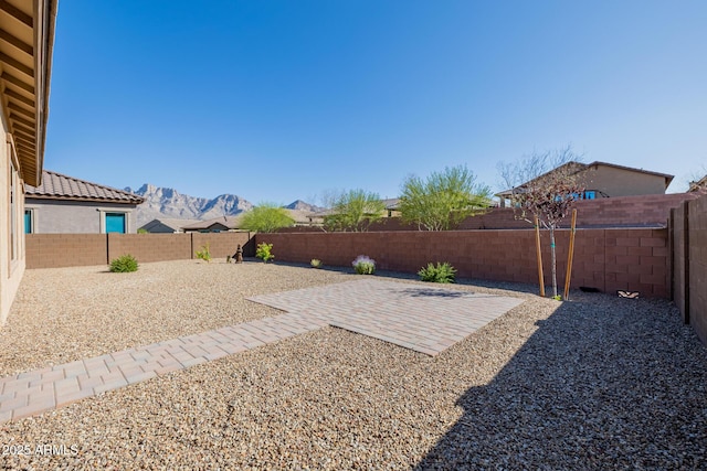 view of yard with a patio area, a fenced backyard, and a mountain view