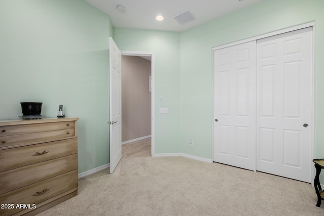 bedroom with a closet, light colored carpet, baseboards, and visible vents