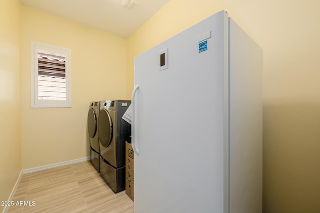 washroom with baseboards, washer and dryer, and laundry area