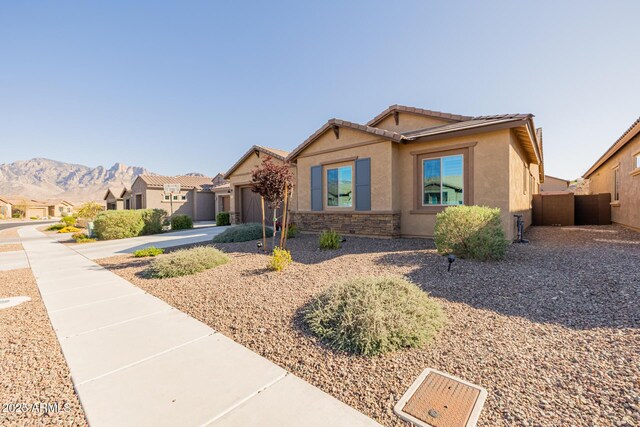 ranch-style house featuring a garage, stucco siding, stone siding, a mountain view, and concrete driveway