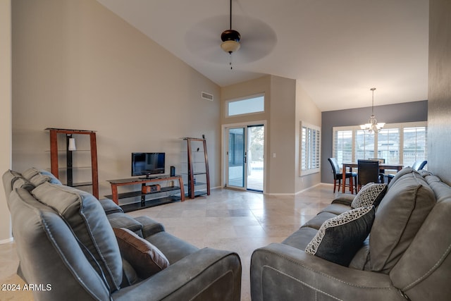 tiled living room with ceiling fan with notable chandelier and high vaulted ceiling