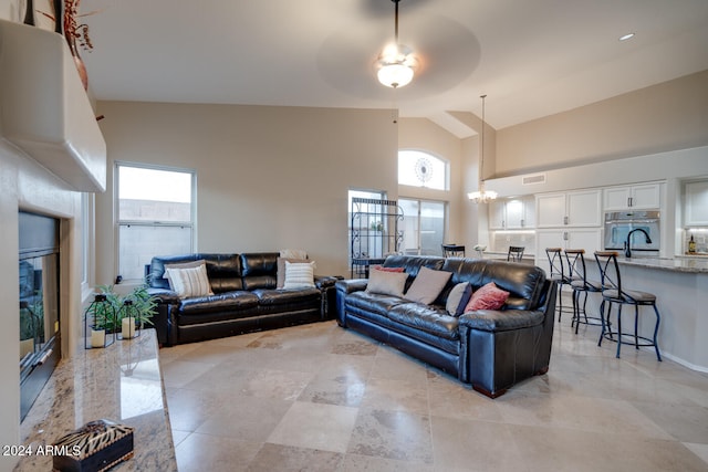 living room featuring plenty of natural light, ceiling fan with notable chandelier, and high vaulted ceiling