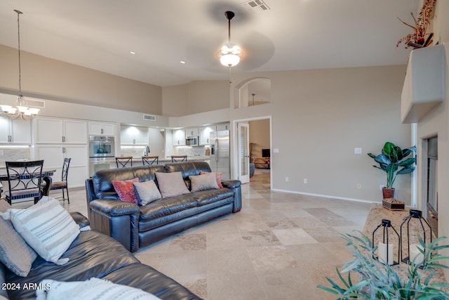 living room featuring ceiling fan with notable chandelier and high vaulted ceiling