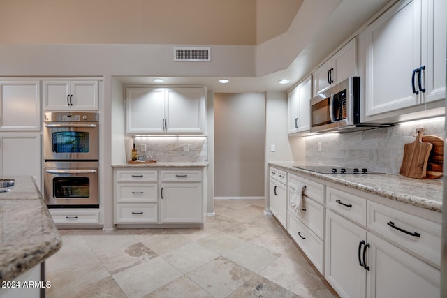 kitchen with white cabinetry, decorative backsplash, stainless steel appliances, and light stone counters