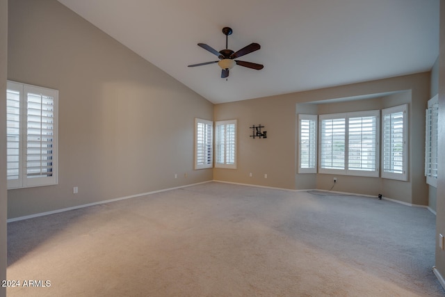 empty room with ceiling fan, light carpet, a wealth of natural light, and vaulted ceiling