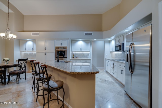 kitchen featuring tasteful backsplash, light stone counters, stainless steel appliances, pendant lighting, and white cabinetry