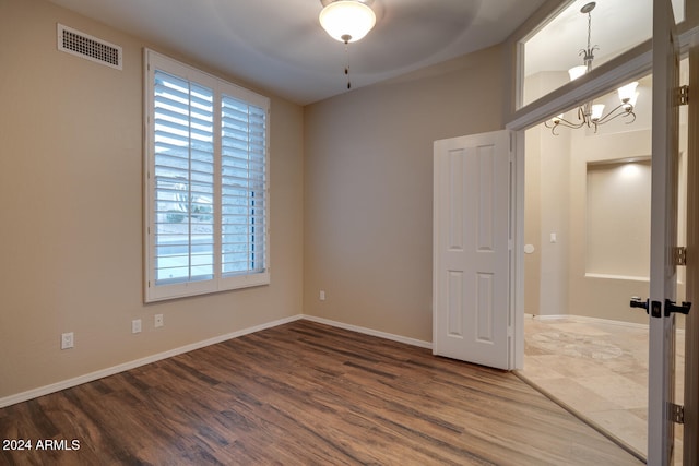 empty room featuring ceiling fan with notable chandelier and hardwood / wood-style flooring