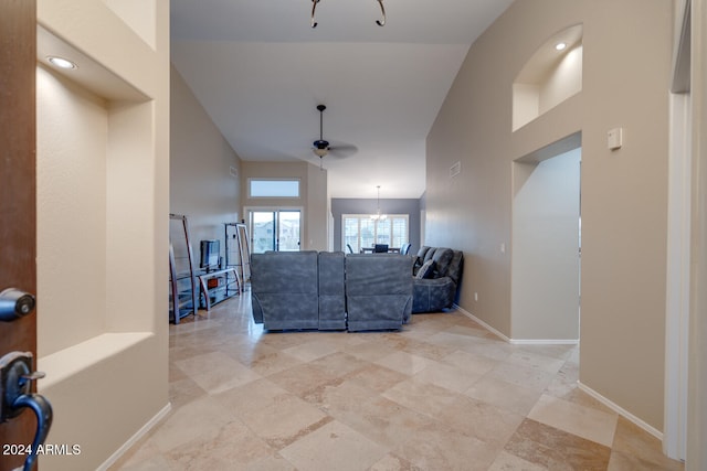 living room with vaulted ceiling and ceiling fan with notable chandelier