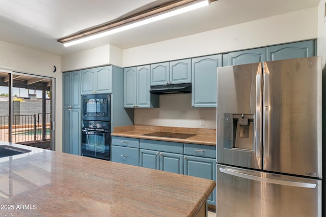 kitchen with black appliances, blue cabinetry, under cabinet range hood, and light countertops