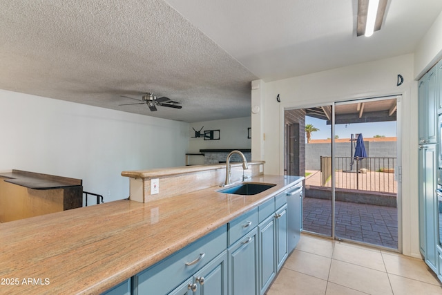 kitchen featuring a sink, blue cabinetry, stainless steel dishwasher, a ceiling fan, and light countertops