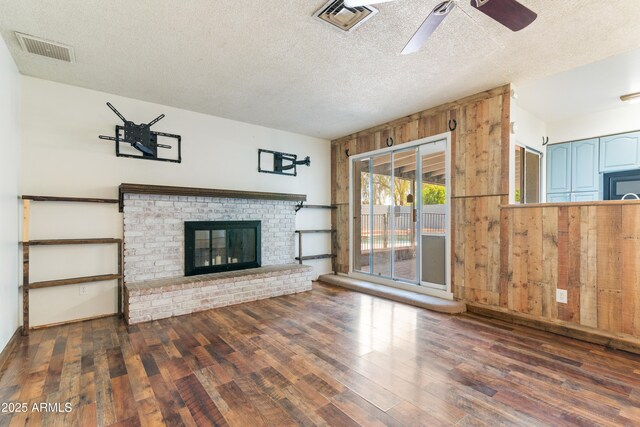 unfurnished living room with wood finished floors, ceiling fan, a textured ceiling, and a fireplace