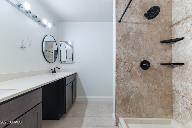 full bath with a tile shower, double vanity, tile patterned floors, and baseboards