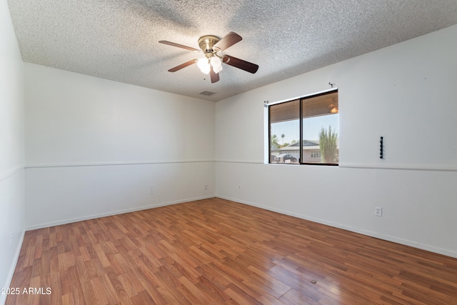 unfurnished room featuring wood finished floors, a ceiling fan, a textured ceiling, and baseboards