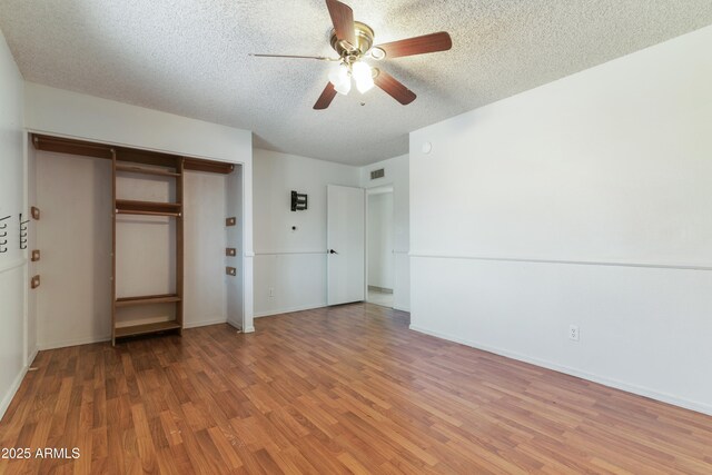 unfurnished bedroom featuring light wood-style floors, a closet, a textured ceiling, ceiling fan, and baseboards