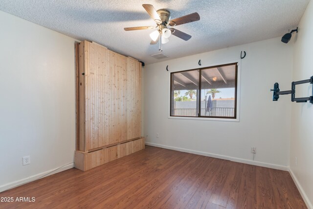 spare room with wood finished floors, a ceiling fan, baseboards, and a textured ceiling
