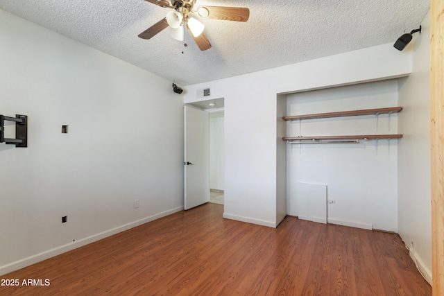 unfurnished bedroom with wood finished floors, a textured ceiling, baseboards, and ceiling fan