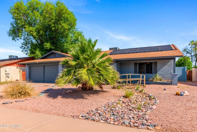 single story home with solar panels, concrete driveway, and fence