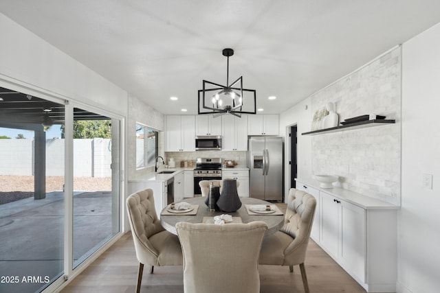 dining area featuring light wood-type flooring, a notable chandelier, and recessed lighting