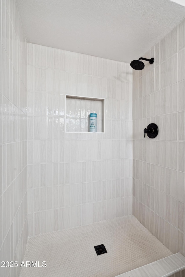 full bathroom featuring a textured ceiling and tiled shower