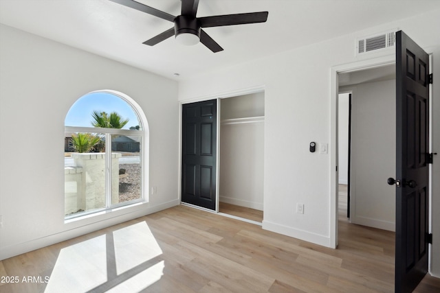 unfurnished bedroom featuring a closet, visible vents, light wood-style flooring, and baseboards