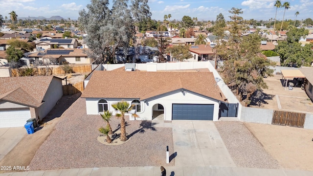 view of front of property with an attached garage, a residential view, fence, and concrete driveway