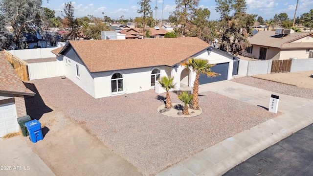 view of front of house featuring a shingled roof, concrete driveway, a residential view, fence, and stucco siding