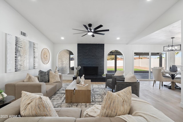 living area featuring recessed lighting, a fireplace, wood finished floors, visible vents, and vaulted ceiling