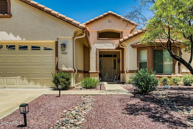 view of front of property featuring an attached garage, stucco siding, a tile roof, and concrete driveway
