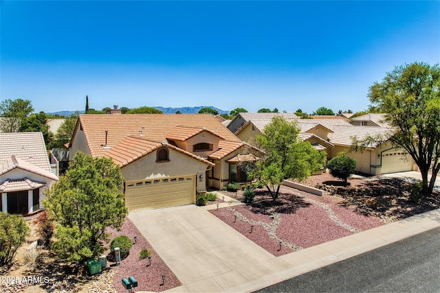 view of front of house with a tiled roof, driveway, a garage, a mountain view, and stucco siding