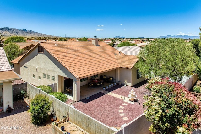 exterior space with stucco siding, a fenced backyard, a mountain view, a patio area, and a tiled roof