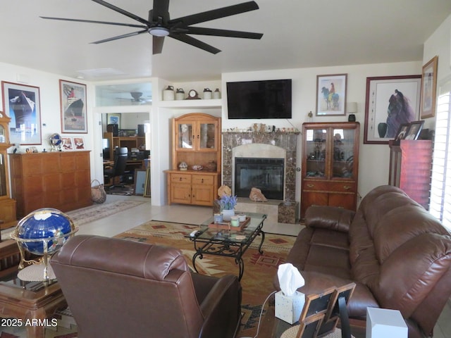 living area with a tiled fireplace and ceiling fan