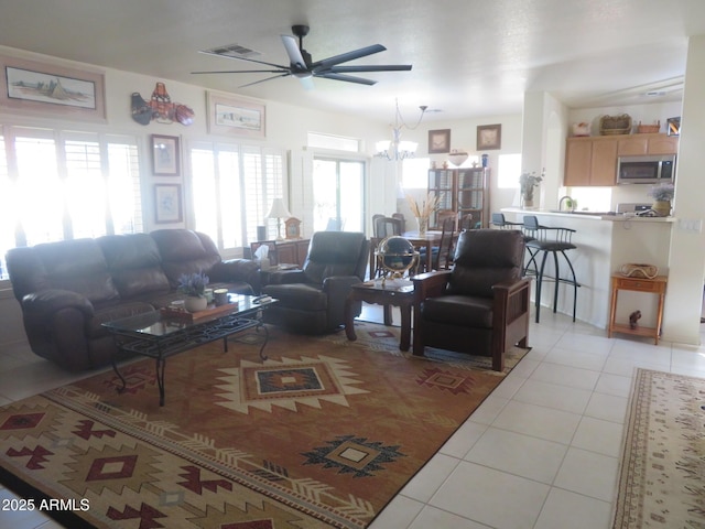 living room with visible vents, ceiling fan with notable chandelier, and light tile patterned floors