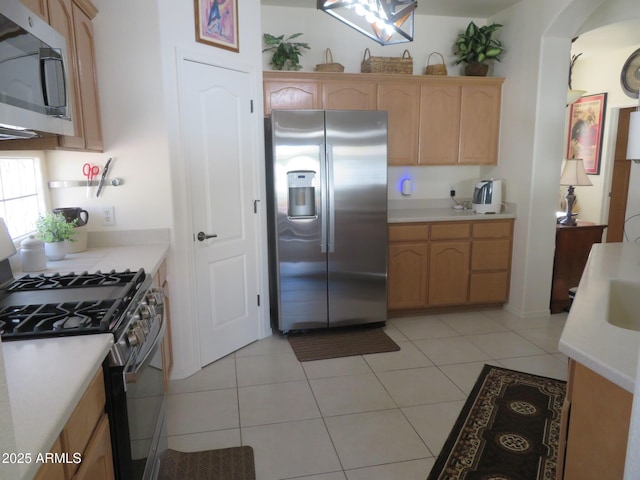 kitchen with light countertops, stainless steel appliances, arched walkways, and light brown cabinets