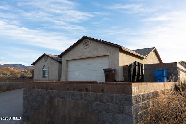 view of front of property with an attached garage, fence, a mountain view, and stucco siding