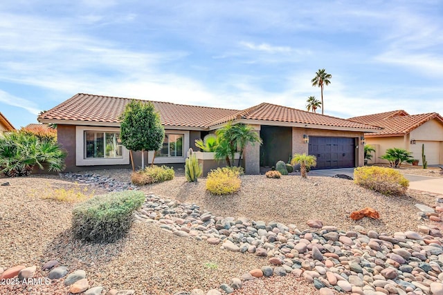 view of front of property featuring a garage, driveway, a tiled roof, and stucco siding