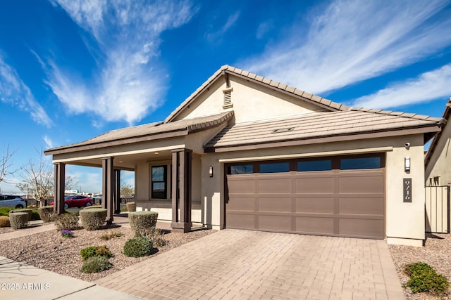 view of front of home with a porch, decorative driveway, an attached garage, and stucco siding