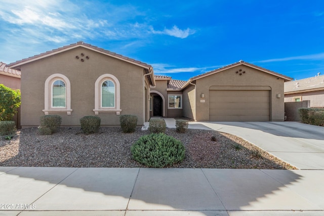 mediterranean / spanish-style house featuring a garage, driveway, a tiled roof, and stucco siding