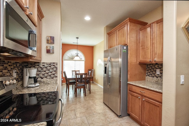 kitchen with decorative backsplash, light stone counters, stainless steel appliances, and decorative light fixtures