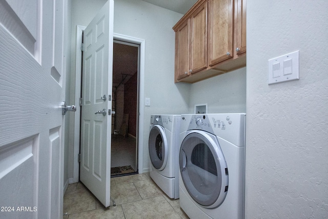 laundry room featuring cabinets, light tile patterned floors, and independent washer and dryer