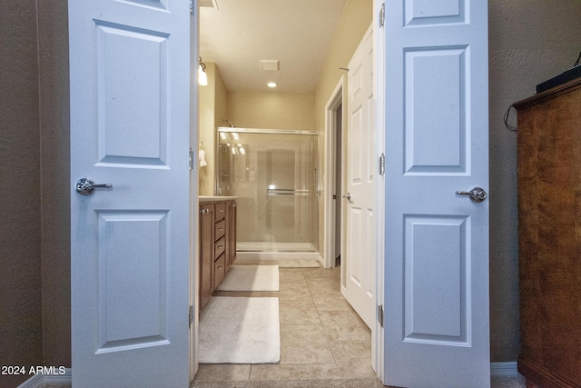 bathroom with tile patterned flooring, vanity, and a shower with door