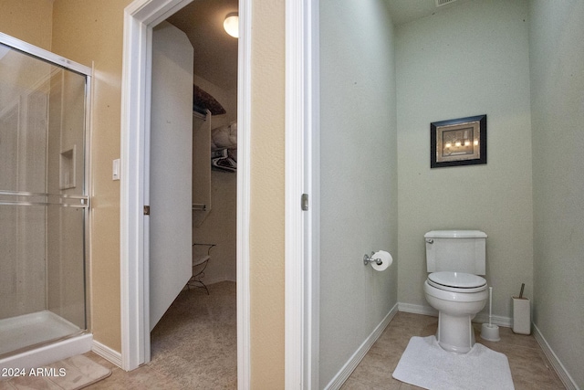 bathroom with a shower with door, tile patterned flooring, and toilet