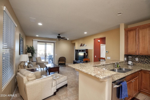 kitchen featuring sink, stainless steel dishwasher, tasteful backsplash, light stone counters, and kitchen peninsula